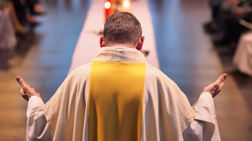 Rear view of a priest with his head bowed and palms extended upward