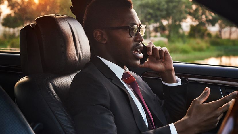 Serious young businessman talking on his cell phone in the driver's seat