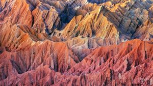 Jagged desert mountains, colored red and orange by sand and sunset