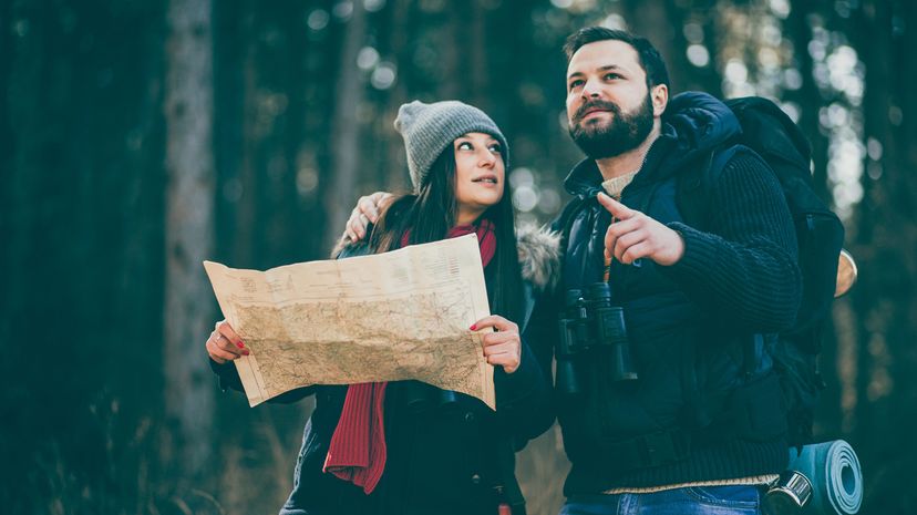 Man points at directions for camping while woman holds map and looks at him skeptically