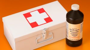 a bottle of hydrogen peroxide beside a closed first aid kit