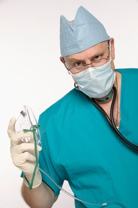 A doctor holds a mask to deliver anesthesia in gas form.