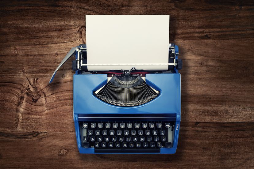 A blue laptop with black keys on a dark, wooden surface