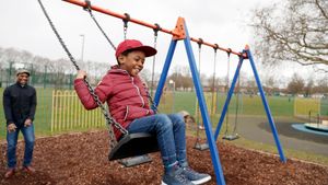 Father and son playing on the swings in the park
