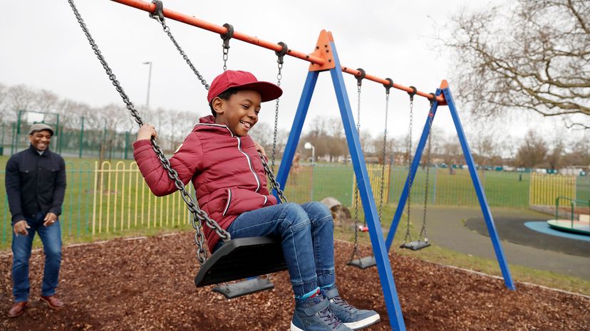 Father and son playing on the swings in the park