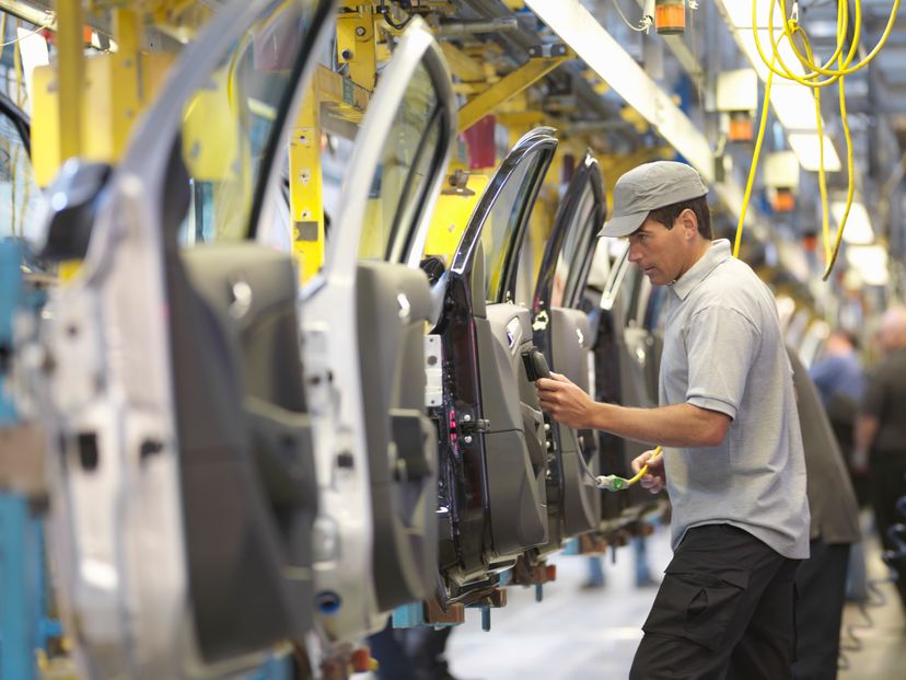 A man inspects car doors in a manufacturing assembly line.