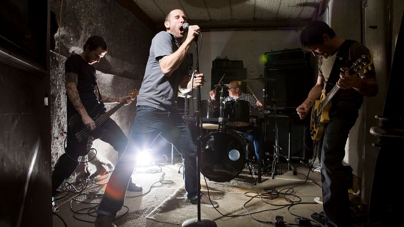 Four musicians in a rock band practice in a small room