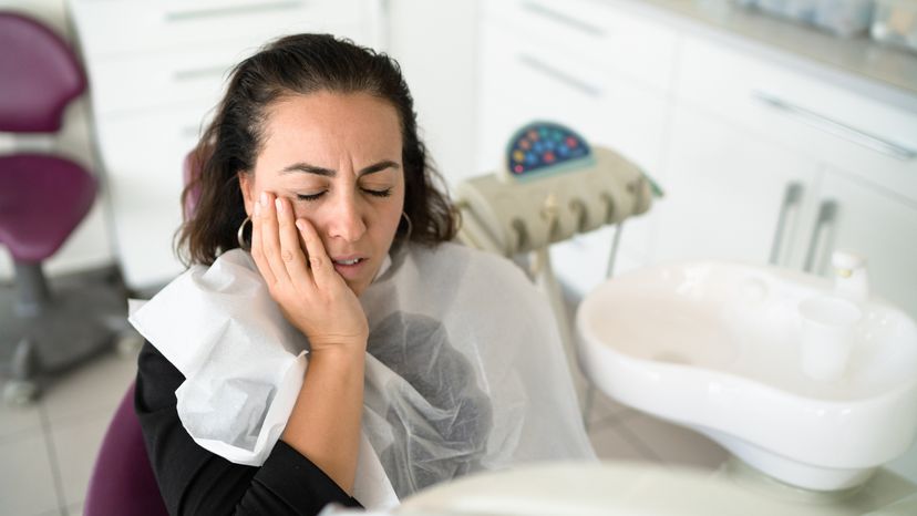 A young woman having toothache in the dentist’s chair