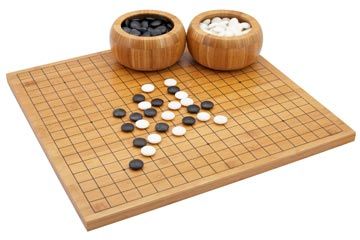 A Go board, two bowls for Go stones, and several black and white stones already played on the board.