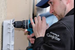 A Google Fiber technician installing a fiber optic box at a residential home.