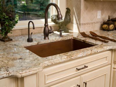 Luxurious kitchen elements including a hammered copper sink basin and granite counter tops.