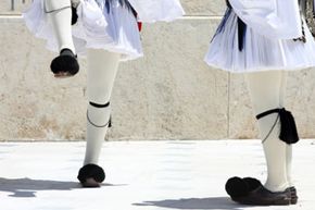 The uniform for the Evzones, the Greek presidential guard, includes a white pleated foustanella and pointed shoes called tsarouhia that are topped with pompons.
