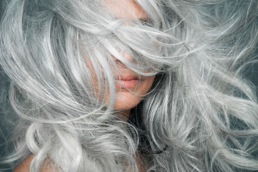 Woman with long, silvery, grey hair blowing across her face.