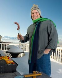 Man grilling sausage in the snow.