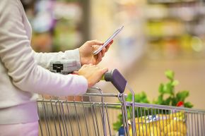 woman texting with grocery cart