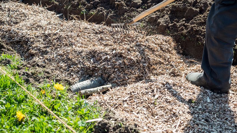 A raised bed of hugelkultur being raked over.