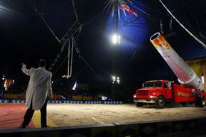 human cannonball being shot from truck in circus ring