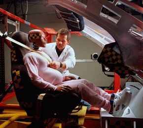 A pregnant crash test dummy is fitted with a seatbelt prior to a test.