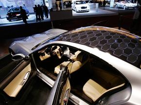 It's too difficult and expensive for solar panels to power the motors in hybrid cars, so they typically assist smaller systems like the air-conditioning unit. Fisker, makers of the luxury hybrid Karma, offer solar panels as an option.