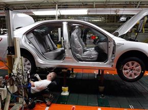 A significant amount of energy goes into producing hybrid cars, but it's no more than what it takes to make conventional cars. Above, production team member Jeff Brangers works on the under carriage of a Toyota Camry Hybrid.