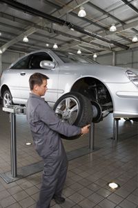 Mechanic holding tire, preparing to service brake system.