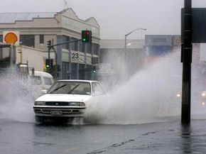 Cars spray water in downtown Auckland, New Zealand, as they drive through deep puddles during heavy rain.