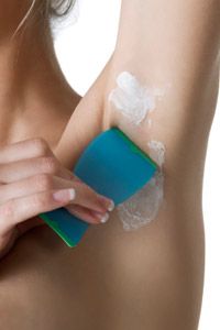 Woman using hair removal cream applied to underarm.