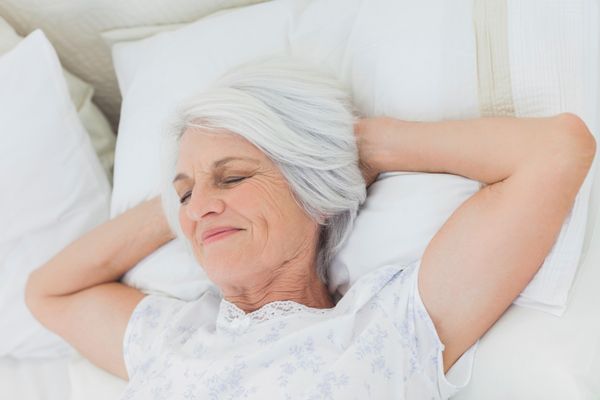 A woman with white hair relaxes in bed.