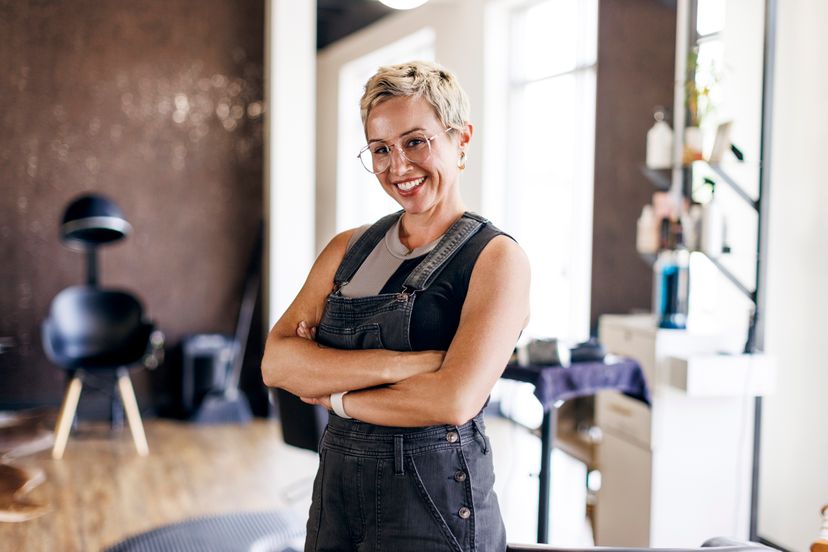 Portrait of hairstylist standing with arms crossed at salon