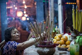 在2015年8月14日在香港举行的饥饿幽灵节期间，一名崇拜者在公园里提供礼物。“border=