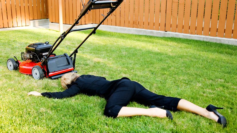 A blonde business woman laying on the grass while mowing lawn