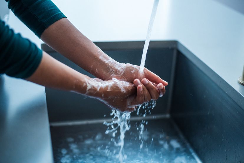 Woman washing her hands in a modern kitchen sink.