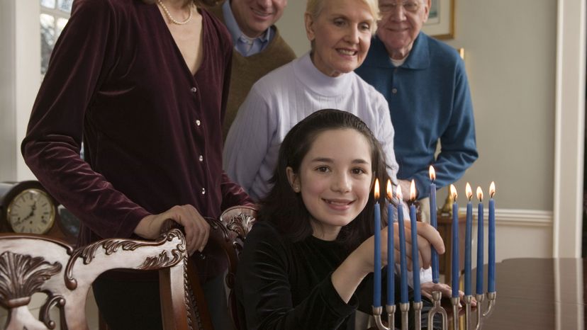 Little girl lighting menorah