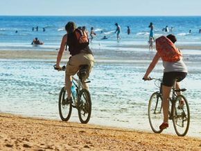 夫妇在海滩上骑自行车”width=