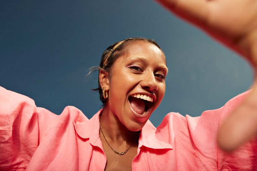 Portrait of cheerful young woman screaming against sky