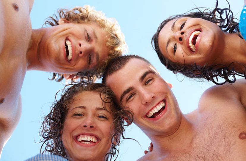 Happy people smile in a huddle on a beach.