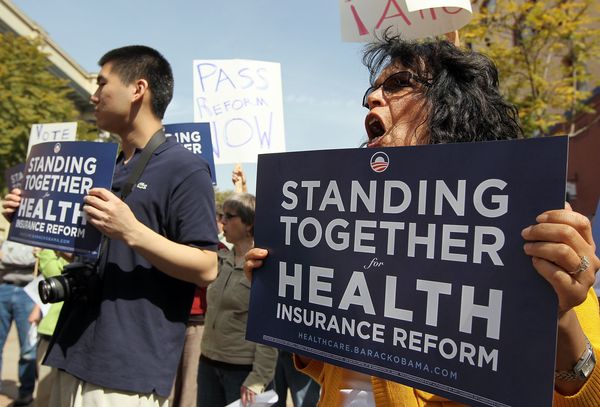 people holding signs about health insurance reform