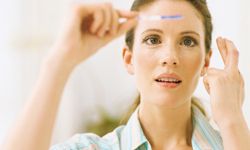 woman looking at pregnancy test with fingers crossed