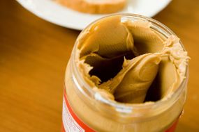 Jar of open peanut butter adjacent to breakfast toast