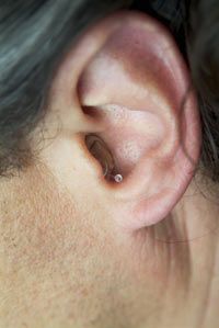 Some hearing aids are bar­ely visible. See more