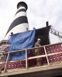 The Cape Hatteras lighthouse on its intricate moving system with a worker in the foreground.