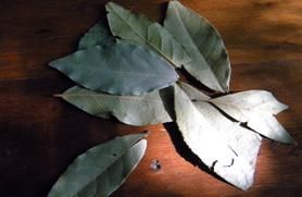 Dried bay leaves in a pile on a wooden surface.&nbsp;