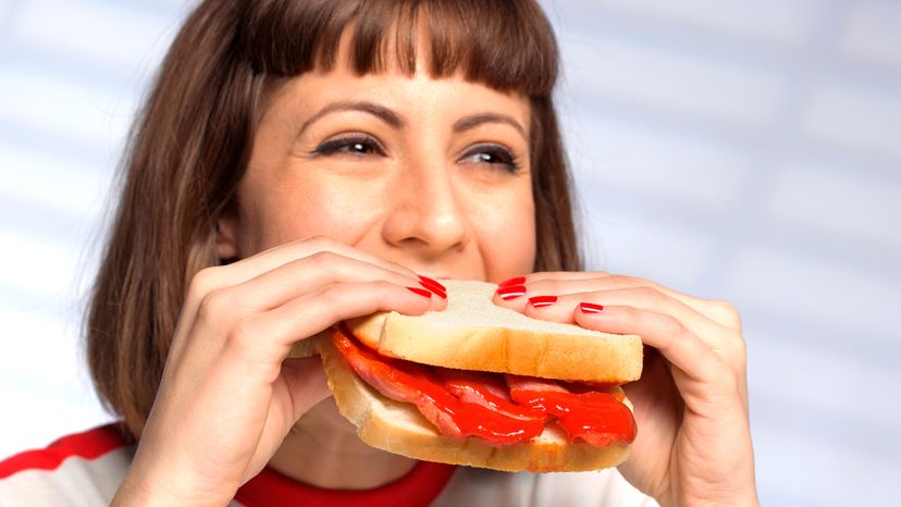 A woman eating sandwich and bacon