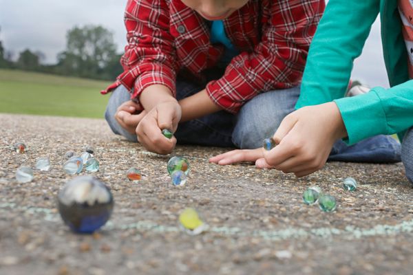 A boy and a girl play marbles.