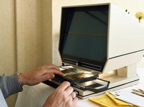 A person sits at a table using a microfiche machine.