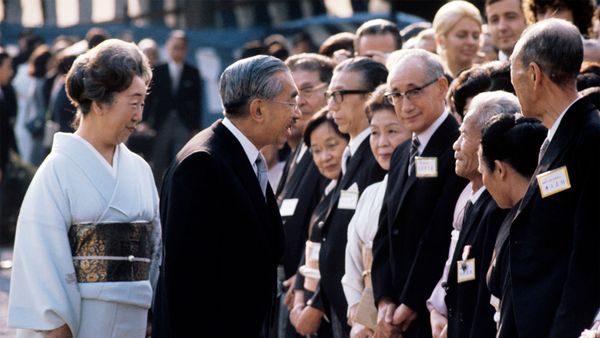 Men in suits mingling in a crowded outdoor business setting.