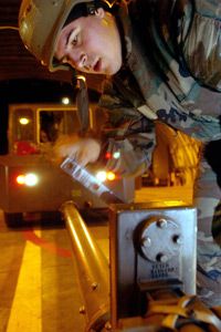 US Airman tightens crank connecting F-16 to a tow truck.