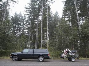 A trailer tows a motorcycle using a hitch jack. 