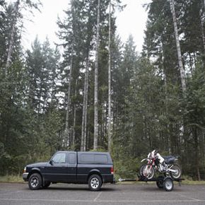 A truck towing a motorcycle on rural road.