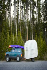 An SUV tows a trailer on a rural road.